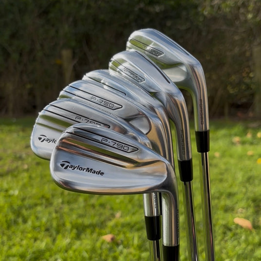 TaylorMade P790 forged iron set golf clubs displayed on grass.
